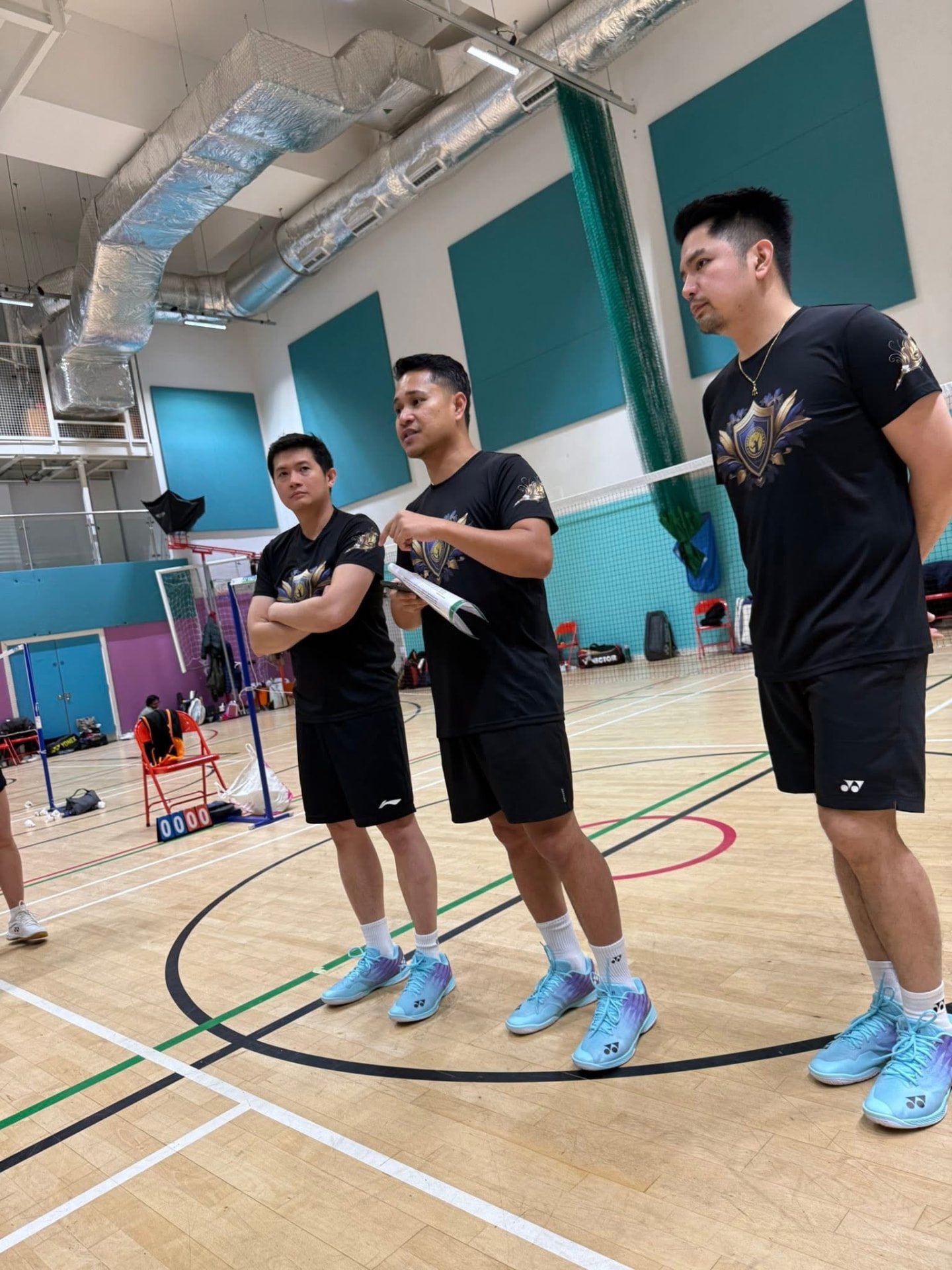Organisers in Smash Potatoes crest shirts talking courtside